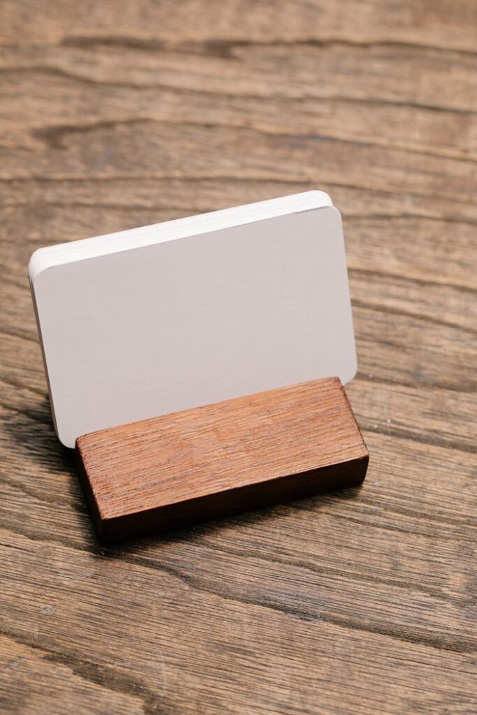 pexels-photo-7318929 Close-up of a blank business card in a wooden holder on a rustic wooden surface, ideal for mockups.